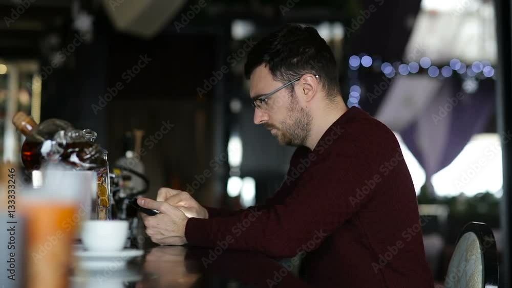 A young man uses tablet while sitting at the bar A young man uses tablet while sitting at the bar