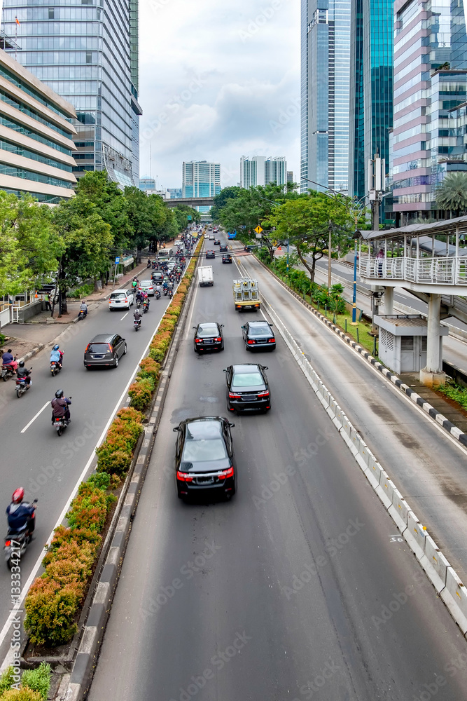 Photo of big road in Jakarta and its traffic, consist of car and motorcycle,  with skyscraper buildings in the both side of the road. Captured in Rasuna Said Street, Indonesia.