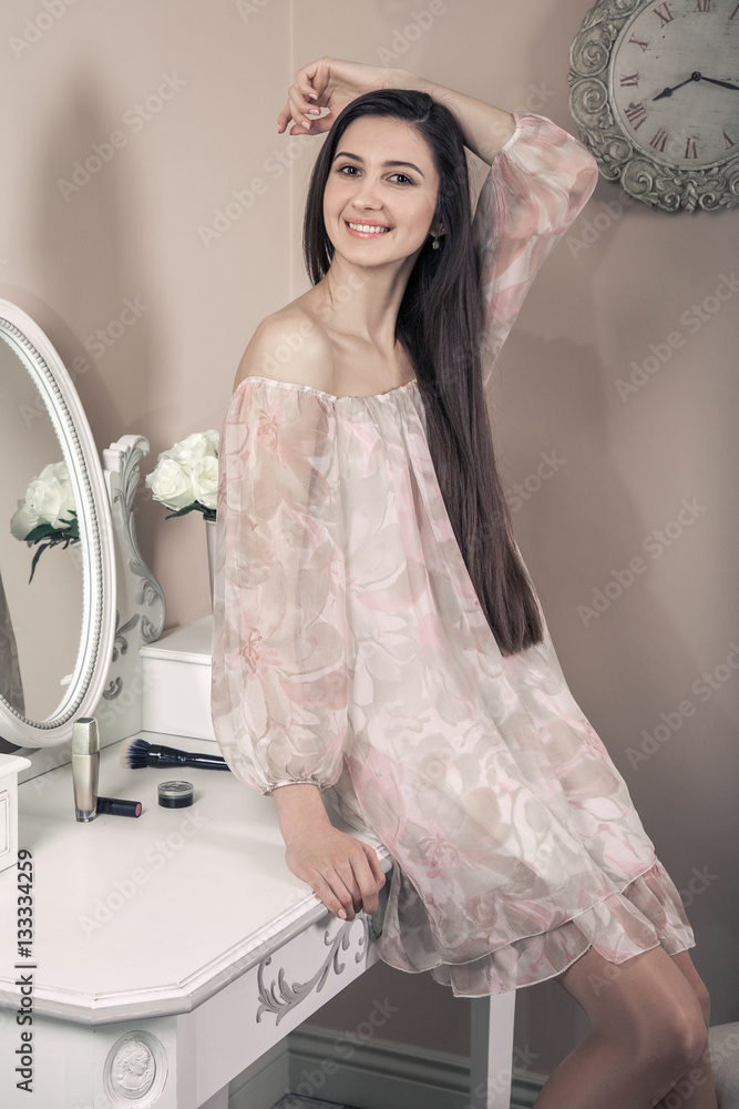 Φωτογραφία Beautiful happy woman with pink dress and long black hair in her room near her dressing table posing before party