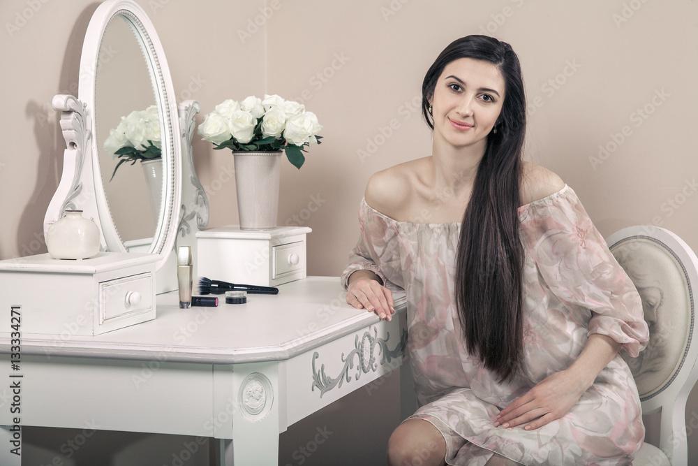 Φωτογραφία Beautiful happy woman with pink dress and long black hair in her room near her dressing table posing before party
