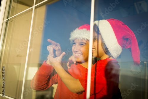 Two cute boys brothers on window waiting for Santa and New Year