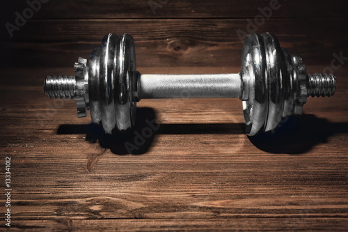 Metal collapsible dumbbell on wooden background