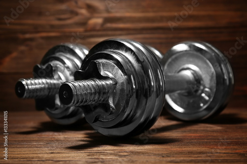 Metal collapsible dumbbells on wooden background, closeup