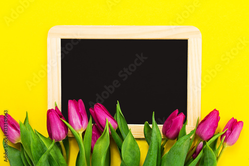 Fresh beautiful lila tulips on yellow colorful background with c