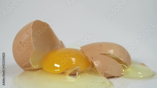 Egg breaking after being dropped to reveal broken shell and egg yolk 