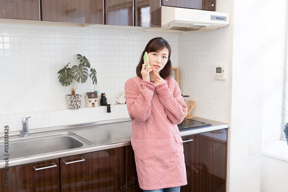 キッチンで電話をする女性 考える キッチンで電話をする女性 考える