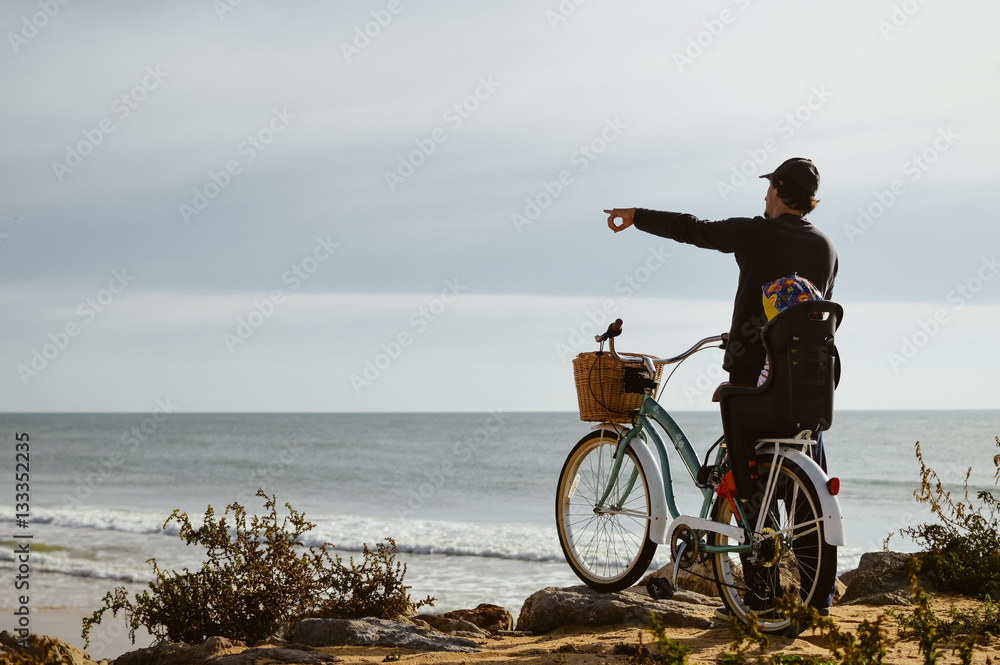 Fototapeta premium Defocused silhouette of child and father with bike on a beach natural outdoor. Travel vacation background