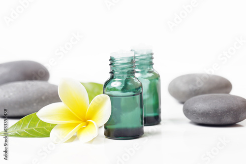 Green cosmetic bottles with zen stones and frangipani flower