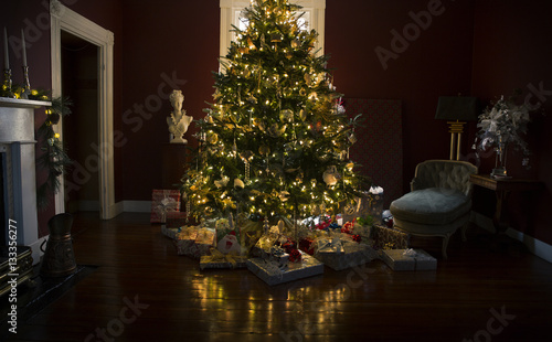 Christmas tree with presents and lights reflected on the wooden floor