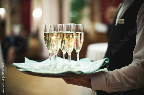 Waiter serving champagne on a tray at the hotel restaurant