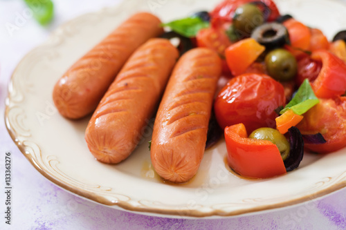 Sausages grilled with vegetables in the Greek style on plate.
