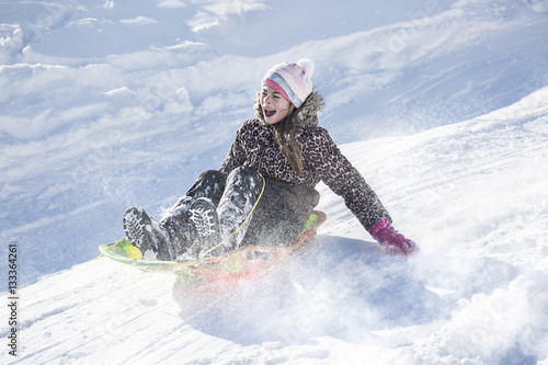 Fotografie Happy and excited girl Sledding downhill on a snowy day