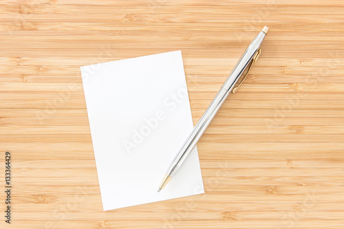 Notepaper with pen put on wooden desk