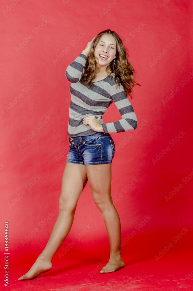 Young cheerful girl in denim shorts and a striped sweater walking in the youthful style
Young cheerful girl in denim shorts and a striped sweater walking in the youthful style