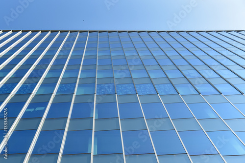 Modern office building wall made of blue glass and steel frame with blue sky