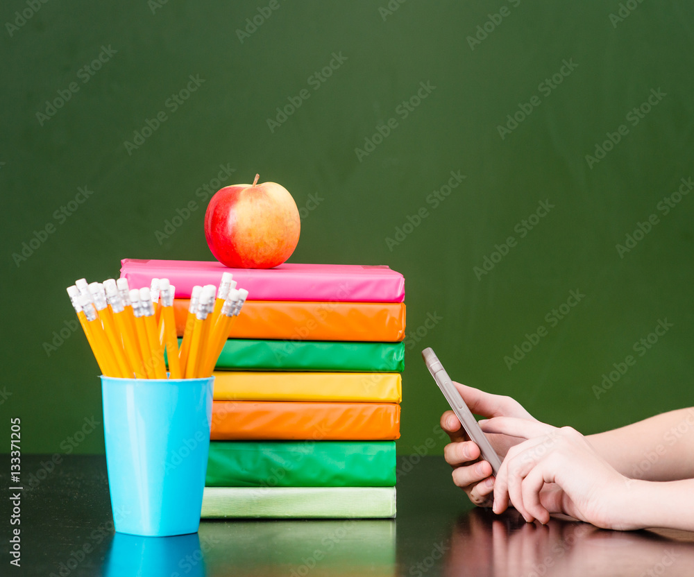 Hands used on the phone near books and green chalkboard. Sample Hands used on the phone near books and green chalkboard. Sample
