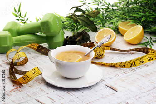 ginger tea - fitness liefestyle concept with tea, dumbells and measure tape photo