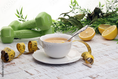 ginger tea - fitness liefestyle concept with tea, dumbells and measure tape photo