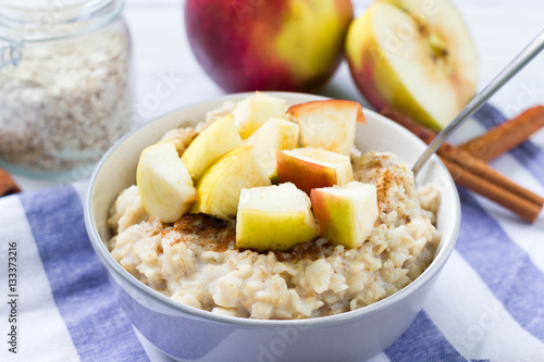 Obraz na płótnie Oatmeal with apple and cinnamon on blue table cloth.