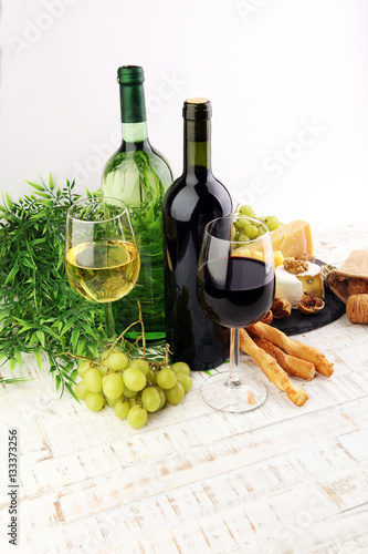 Bottle of white wine, grape and corks on wooden table