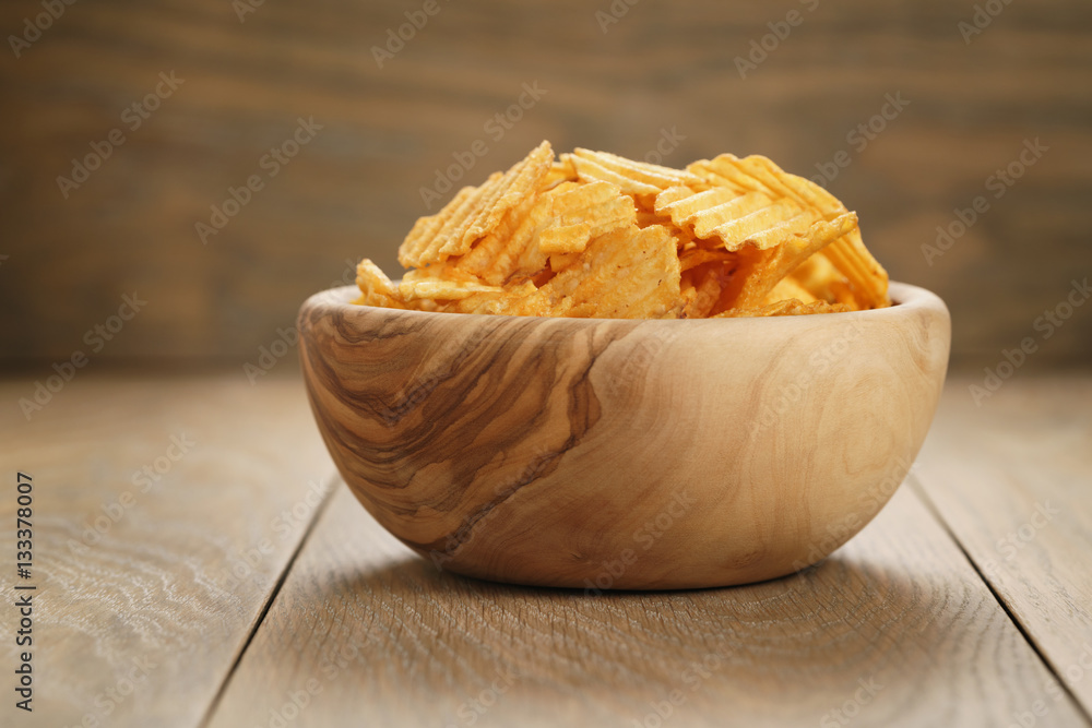 rippled potato chips with paprika in wooden bowl, with copy space rippled potato chips with paprika in wooden bowl, with copy space