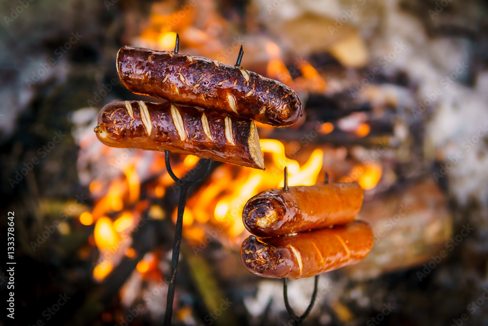 delicious sausages baked on a campfire in the forest