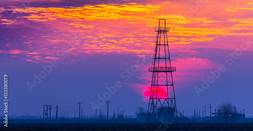 Oil and gas rig profiled on sunset sky