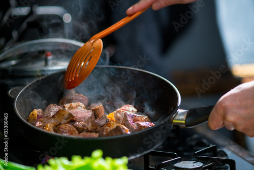 Fényképezés Man mixing the meat in a frying pan shovel