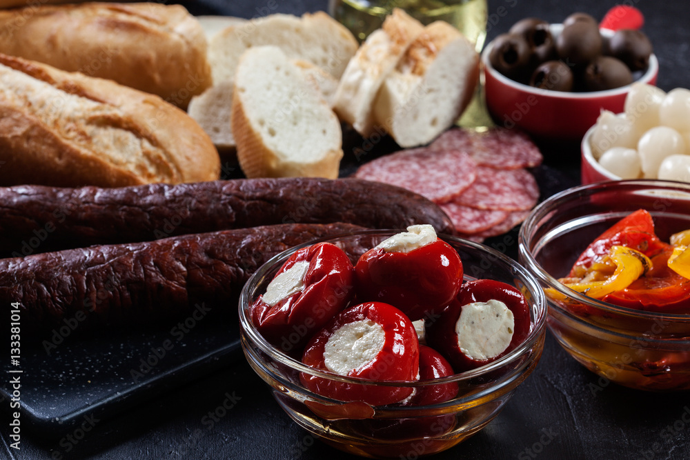 Spanish tapas with slices jamon serrano and grilled pepper. Also olives, salami, pickled onions, and peppers stuffed with cheese Spanish tapas with slices jamon serrano and grilled pepper. Also olives, salami, pickled onions, and peppers stuffed with cheese