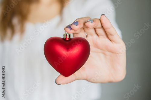 Young woman holding red heart decoration. Love concept.