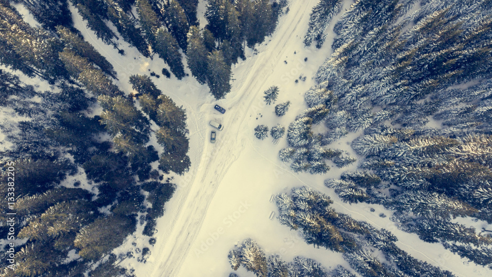 Fototapeta premium Aerial view of snow covered road through a forest.
