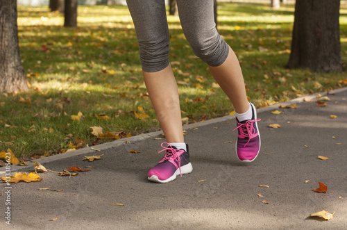 Runner woman feet running on road closeup on shoe. Fitness woman in training shoes jogging outdoors in park. Sport active lifestyle, Bright running shoes