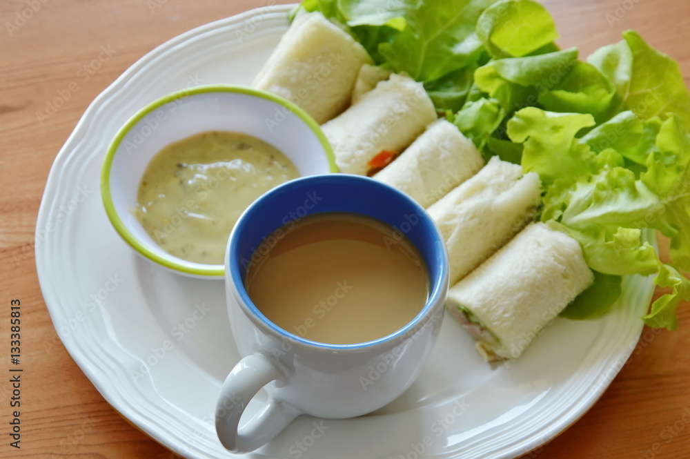 roll bread filled bologna and green oak with coffee on dish roll bread filled bologna and green oak with coffee on dish