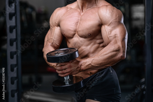 Handsome bodybuilder training in the gym sexy man lift dumbbells
