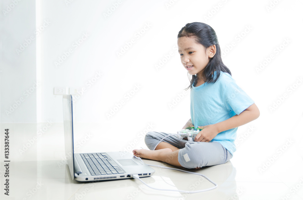 Asian little girl playing games with laptop computer and joystic