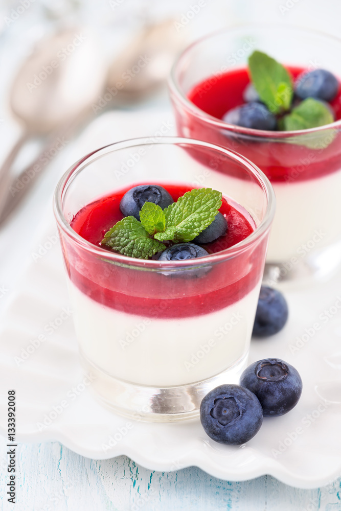 Delicious Italian dessert Panna Cotta for two with fresh blueberries and raspberry coulis in small transparent glasses for Valentine’s day Delicious Italian dessert Panna Cotta for two with fresh blueberries and raspberry coulis in small transparent glasses for Valentine’s day