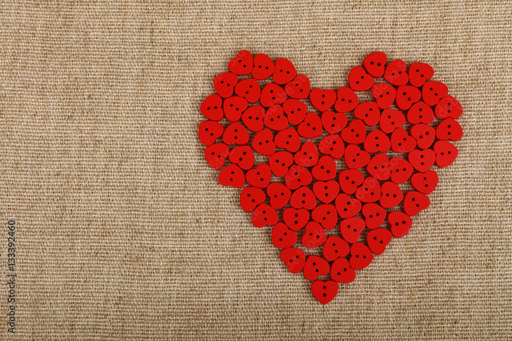 Red heart shaped sewing buttons on canvas