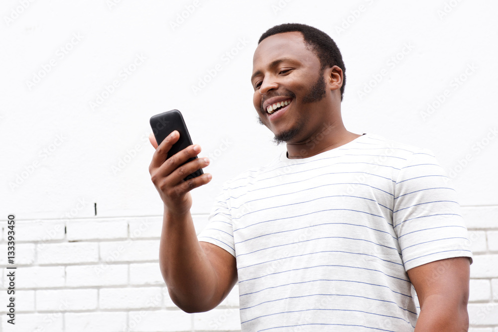 cool smiling young black man looking at mobile phone cool smiling young black man looking at mobile phone