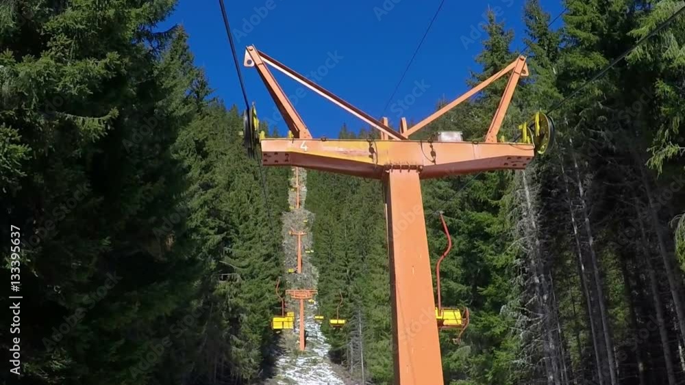 Slow motion Panning up shot of an obsolete chair ski lift transportation system which skiers transport while suspended off ground with GoPro Hero 4 stabilized by handheld gimbal. Cable catchers (meta Slow motion Panning up shot of an obsolete chair ski lift transportation system which skiers transport while suspended off ground with GoPro Hero 4 stabilized by handheld gimbal. Cable catchers (meta
