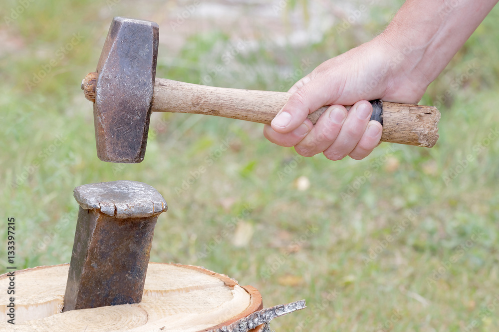 Hand holding a sledgehammer, splitting a birch log Hand holding a sledgehammer, splitting a birch log