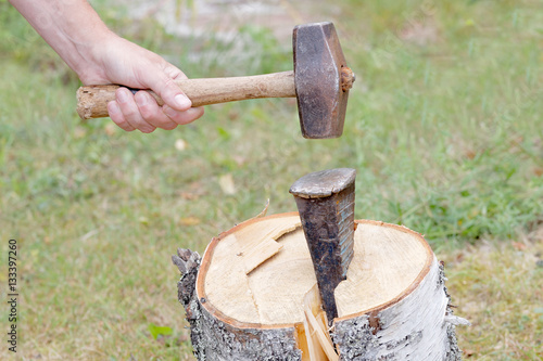 Hand holding a sledgehammer, splitting a birch log