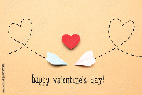 On love wings / Creative valentines concept photo of two paper planes and a heart on brown background.
