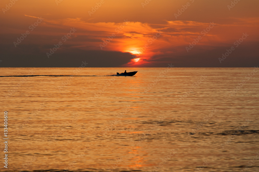 Naklejka premium Boot am Horizont vor untergehender Sonne