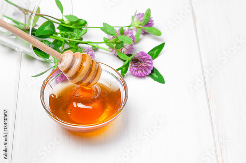 Honey and wild flowers on white wooden background