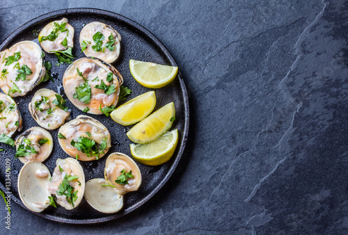Raw clams with lemon, herbs and white wine, slate background photo