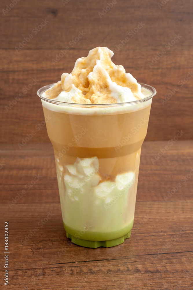 Matcha and espresso frappe in the plastic glass on wooden background