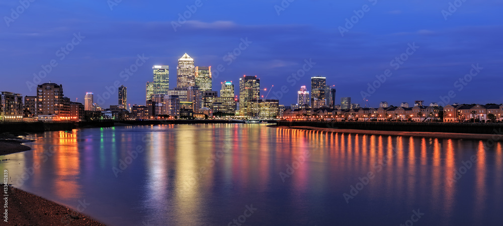 Obraz premium Canary Wharf business district in London at night over Thames River.