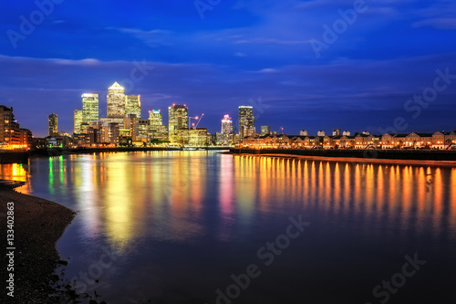 Canary Wharf business district in London at night over Thames River.