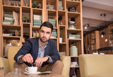 young man stirring coffee cup indoors caffee bar