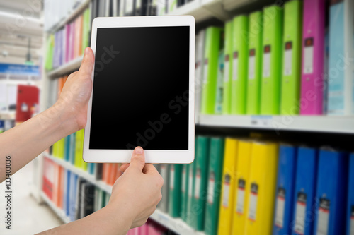 human hand hold and touch smartphone, tablet, cell phone with blurry book store.